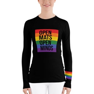 Puede incluir: Camiseta negra de manga larga con un diseño de rayas arcoíris y el texto "OPEN MATS OPEN MINDS".