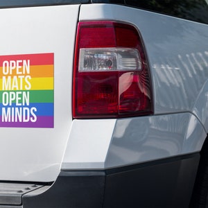 May include: A white car with a rainbow sticker that says "Open Mats Open Minds".
