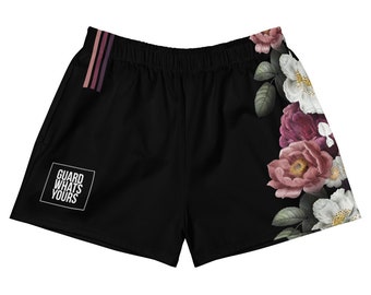 May include: Black athletic shorts with a floral design on the right side. The shorts have a white square with the text "GUARD WHATS YOURS" on the left side. A stripe of pink and purple is on the upper left side.