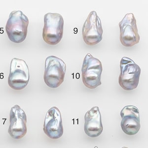 Könnte beinhalten: Eine Sammlung von zwölf unregelmäßig geformten, irisierenden Perlen. Jede Perle zeigt eine einzigartige Form und eine Mischung aus Farben, darunter Weiß, Rosa und Lavendel. Die Perlen sind in drei Reihen zu je vier Stück angeordnet.