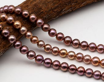 May include: A strand of round, lustrous pearls in shades of mauve, plum, and bronze. The pearls are arranged in multiple rows, displaying a smooth, reflective surface with subtle color variations across each individual bead.