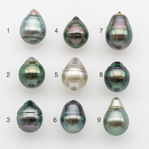 Può includere: Nove perle iridescenti a forma di goccia, in vari colori, tra cui verde, grigio e crema. Ogni perla ha una lucentezza e una forma uniche, su sfondo bianco. Le perle sono numerate da 1 a 9.