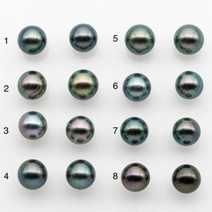 Puede incluir: Ocho perlas oscuras y brillantes dispuestas en dos filas de cuatro. Las perlas exhiben una gama de colores iridiscentes, incluyendo verde, azul y púrpura, con un alto grado de reflectividad superficial. Cada perla es redonda y parece de alta calidad.