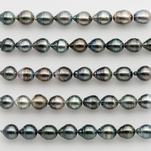 Pode incluir: Cinco fios de pérolas iridescentes em forma de gota. As pérolas variam em cor, do cinza escuro ao prateado e verde. Cada fio é enfiado em um fio fino e transparente, mostrando a beleza natural das pérolas.