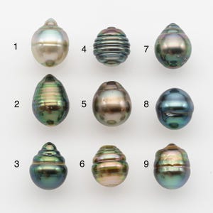 Può includere: Nove perle iridescenti di varie forme e colori sono esposte su sfondo bianco. Le perle variano dal crema chiaro al verde scuro e blu, con trame e motivi unici. Queste perle naturali sono ideali per la creazione di gioielli.