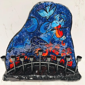 Può includere: Un candelabro a nove bracci in ceramica con uno sfondo blu scuro raffigurante una scena dipinta di una persona che suona il violino, un uccello e una capra. L'opera d'arte è nei toni del blu, del rosso e dell'arancione.