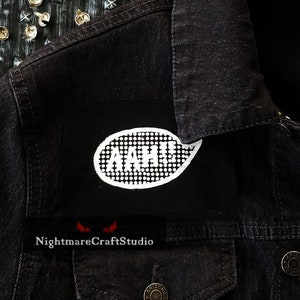 May include: Black denim jacket with a white patch that says "AGGH" in a speech bubble. The patch is sewn onto the jacket's left shoulder.