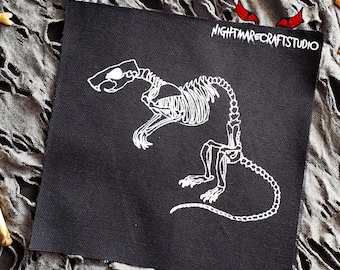 May include: White embroidered rat skeleton on a black fabric patch. The patch has the text "NIGHTMARECRAFTSSTUDIO" in white.