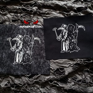 May include: Two black and white iron-on patches featuring a plague doctor holding a staff and a scythe. The patches are on a gray, textured fabric background. The text "NIGHTMARE CRAFTS STUDIO" is visible on one of the patches.
