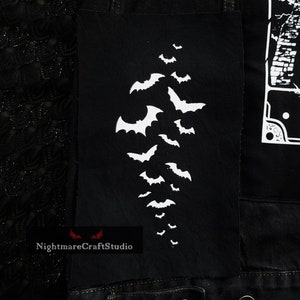 May include: Black denim jacket with a white bat design patch. The patch is on the left side of the jacket and features a cluster of bats flying in a diagonal pattern.