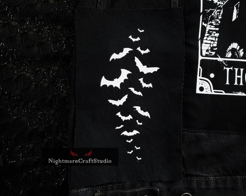 May include: Black denim jacket with a white bat design patch. The patch is on the left side of the jacket and features a cluster of bats flying in a diagonal pattern.