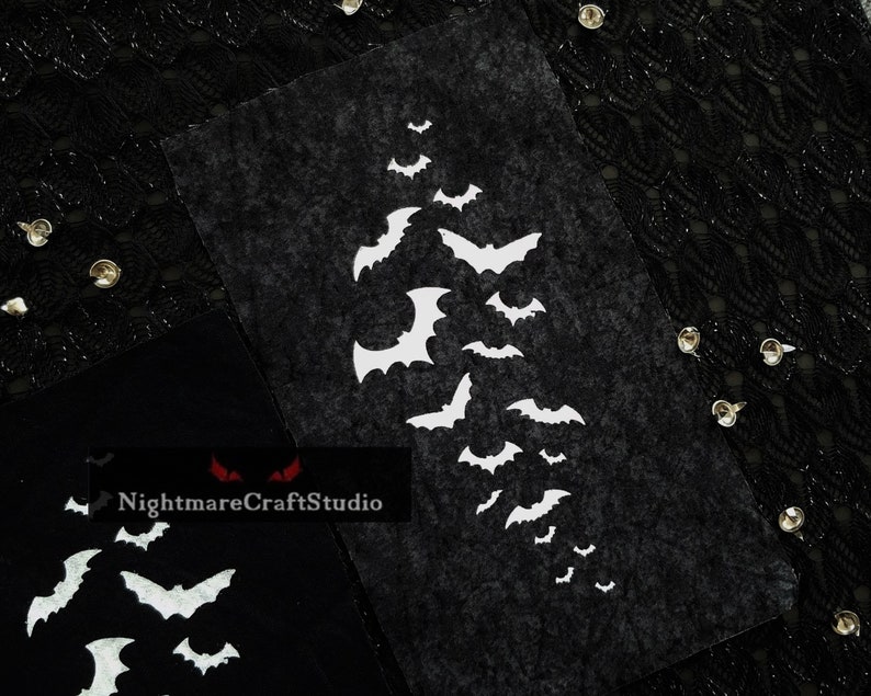 May include: Black felt with white bat silhouettes arranged in a cascading pattern. The bats are of varying sizes and are clustered together in the center of the felt.