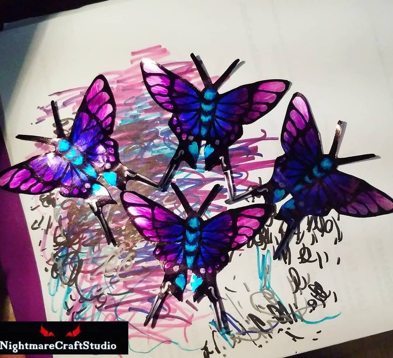 May include: Four iridescent butterflies with purple, blue, and pink wings. The butterflies are arranged in a cluster on a white background with colorful scribbles.