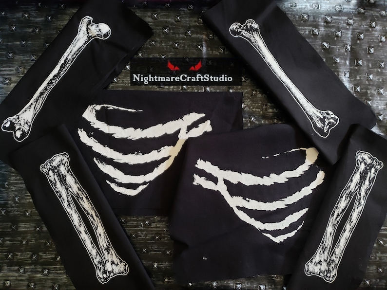 May include: Five black fabric squares with white skeleton bone designs. The designs include a rib cage, a long bone, and a pair of bones. The text "NightmareCraftStudio" is printed on one of the squares.