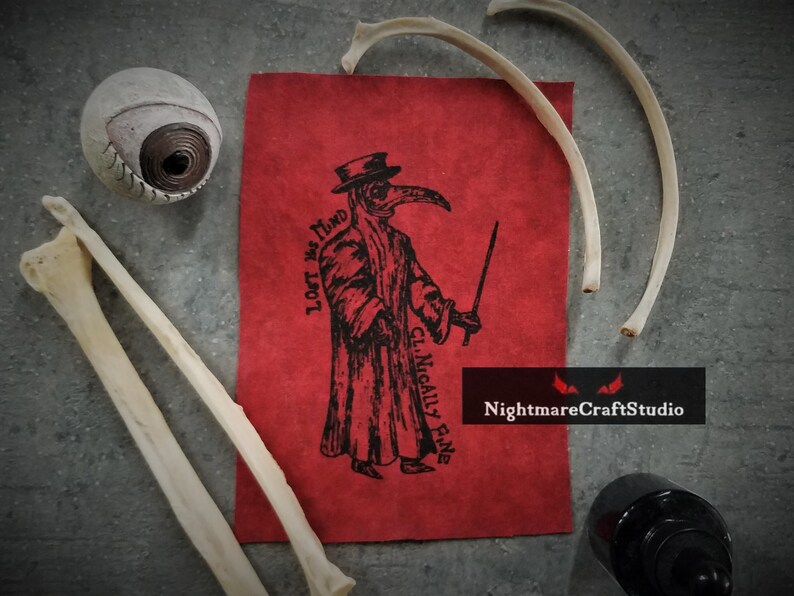May include: A red fabric patch with a black and white illustration of a plague doctor wearing a long coat, a mask with a long beak, and a hat. The text "LOFT vs MIND" and "CL. NICALLY FINE" are printed vertically on the left side of the patch. The text "NightmareCraftStudio" is printed in white on a red background at the bottom of the patch.
