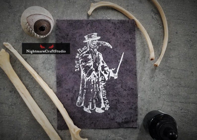 May include: A black and white illustration of a plague doctor with a long beak mask. The text "LOST HIS MIND CLINICALLY FINE" is printed around the figure. The illustration is printed on a dark gray fabric.