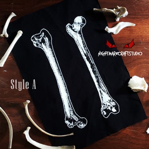 May include: Black fabric with two white bone images printed on it. The text "Style A" is printed in white on the fabric. The fabric is surrounded by several white bones.