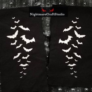 May include: Two black fabric patches with white silhouettes of bats arranged in a vertical line. The text "NightmareCraftStudio" is printed in white on the top right patch.