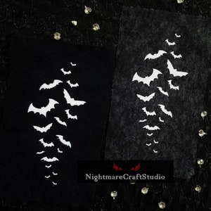 May include: Two black fabric panels with white bat silhouettes cut out. The bats are arranged in a vertical pattern, with the largest bat at the top and the smallest bats at the bottom. The fabric panels are textured and have a slightly distressed look. The text "NightmareCraftStudio" is printed in red at the bottom of the image.