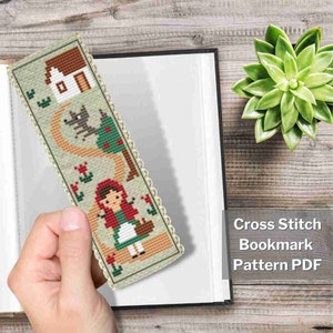 Könnte beinhalten: Kreuzstich-Lesezeichen mit dem Motiv von Rotkäppchen. Das Design zeigt ein Haus, einen Wolf, einen Baum und Rotkäppchen mit einem Korb auf beigem Hintergrund. Der Text "Cross Stitch Bookmark Pattern PDF" ist ebenfalls sichtbar.