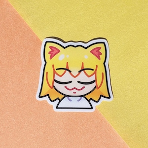 May include: A sticker featuring a cartoon cat girl with yellow hair and red accents. The cat girl has closed eyes and a small smile. The sticker is on a background of orange and yellow.