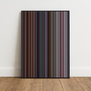May include: A framed art print with a vertical striped design in hues of brown, purple, green, and blue. The artwork is presented in a black frame, set against a white wall and a wooden floor.
