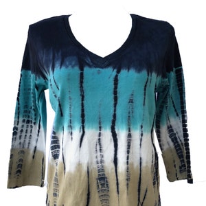 Op de afbeelding: Een langarm, tie-dye shirt met een V-hals. Het shirt is een mix van blauwe, turquoise, witte en bruine kleuren.