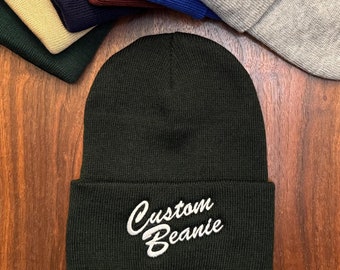 May include: A collection of eight beanies in various colors, including black, green, beige, navy blue, burgundy, blue, and gray. One beanie is black with white embroidery that reads "Custom Beanie".