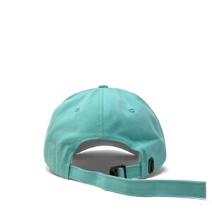 Custom embroidered script hat with personalized text on teal cotton twill dad cap featuring unstructured low profile shape and adjustable strap closure. Clean stitched lettering design on front panel suitable for branding, custom text display and everyday wear. Soft breathable cotton fabric with curved visor and detailed embroidery finish.