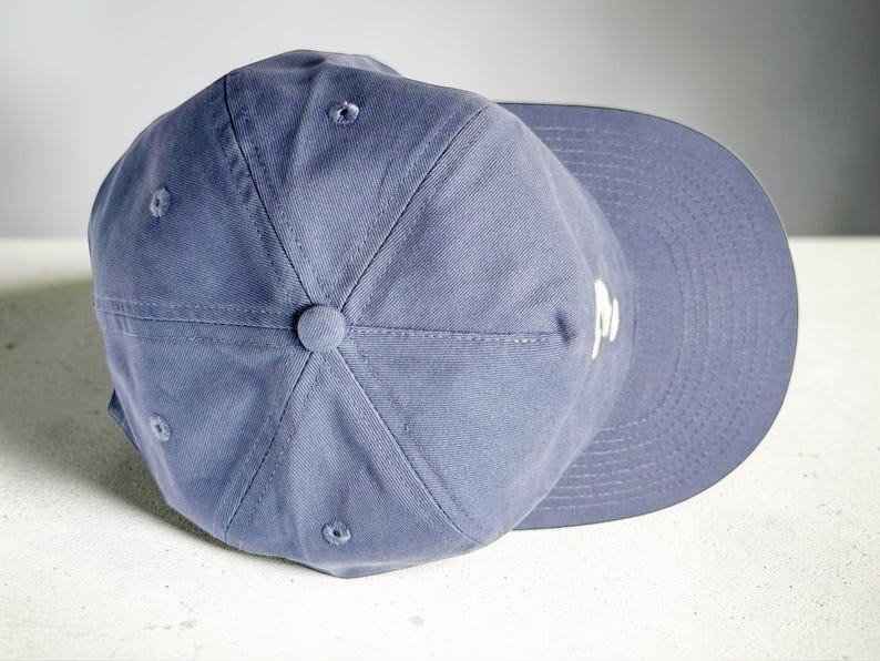 Custom embroidered question mark hat on blue cotton 5 panel snapback cap featuring structured crown and pre curved visor. Clean white embroidery symbol on front panel suitable for custom text, logo placement and daily wear. Adjustable snapback closure provides flexible fit with breathable cotton twill fabric. Product mockup shows front view on neutral background highlighting stitching detail, panel structure and consistent composition for all listing images.