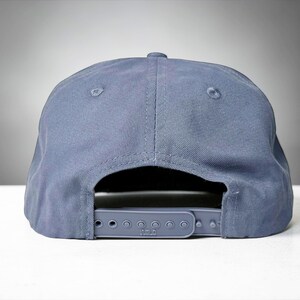 Custom embroidered question mark hat on blue cotton 5 panel snapback cap featuring structured crown and pre curved visor. Clean white embroidery symbol on front panel suitable for custom text, logo placement and daily wear. Adjustable snapback closure provides flexible fit with breathable cotton twill fabric. Product mockup shows front view on neutral background highlighting stitching detail, panel structure and consistent composition for all listing images.