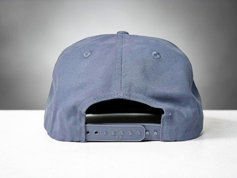 Custom embroidered question mark hat on blue cotton 5 panel snapback cap featuring structured crown and pre curved visor. Clean white embroidery symbol on front panel suitable for custom text, logo placement and daily wear. Adjustable snapback closure provides flexible fit with breathable cotton twill fabric. Product mockup shows front view on neutral background highlighting stitching detail, panel structure and consistent composition for all listing images.
