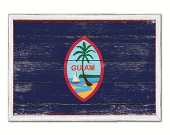 May include: A wooden sign with a white frame featuring the flag of Guam. The flag is blue with a red, white, and blue seal in the center. The seal depicts a palm tree and the word "GUAM".
