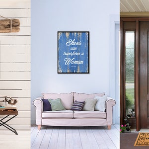 May include: A blue and white sign with the text "Shoes can transform a woman" on a distressed wood background. The sign is hanging on a white wall, a light brown couch, and a brown door.
