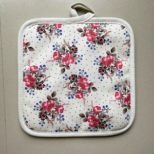 Peut inclure: Un dessous de plat en coton blanc avec un motif floral. Le motif présente des fleurs rouges, des feuilles brunes et des baies bleues sur un fond blanc avec de petits points blancs.