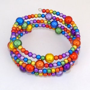 May include: A rainbow-colored beaded bracelet with a silver clasp. The bracelet is made of small, round beads in shades of red, orange, yellow, green, blue, indigo, and violet.