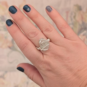 May include: A silver wire wrapped ring featuring a light green sea glass stone.