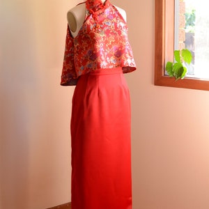 May include: A red halter top with a floral pattern and a matching red skirt. The top has a mandarin collar and a high neckline. The skirt is floor-length and has a fitted silhouette.