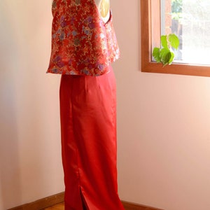 May include: A red and gold brocade top with a high collar and a matching red skirt with a slit in the back. The skirt is floor-length and the top is cropped.