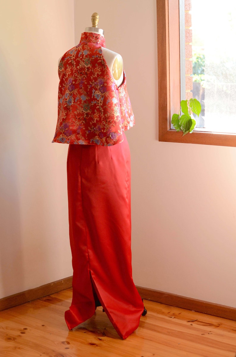May include: A red and gold brocade top with a high collar and a matching red skirt with a slit in the back. The skirt is floor-length and the top is cropped.