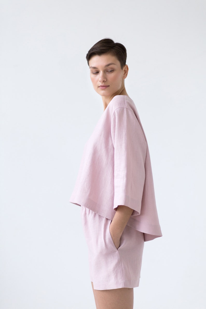 May include: A light pink linen top and shorts set. The top has a relaxed fit and a slightly cropped hem. The shorts have a drawstring waist and pockets.