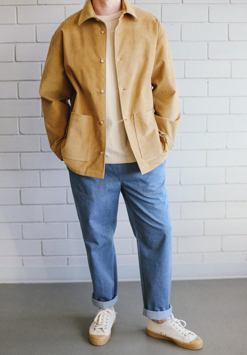 Puede incluir: Chaqueta de pana color canela con dos bolsillos delanteros y botones, combinada con una camiseta crema y vaqueros azul claro. El conjunto se completa con zapatillas blancas con suela color canela. El modelo est&aacute; de pie frente a una pared de ladrillos blancos.