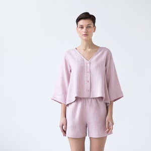 May include: A pink linen pajama set with a short-sleeved button-up top and matching shorts.
