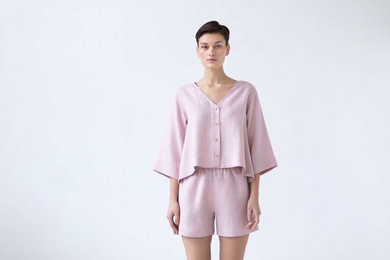 May include: A pink linen pajama set with a short-sleeved button-up top and matching shorts.