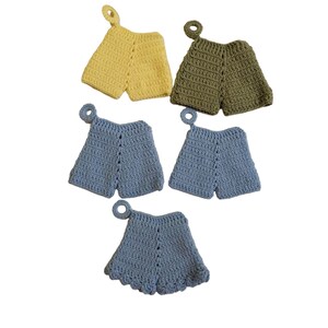 May include: Five crocheted pot holders shaped like shorts. Two are blue, one is yellow, and two are green.