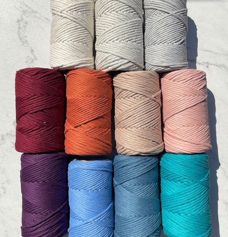 Pode incluir: Dez rolos de cord&atilde;o de algod&atilde;o em v&aacute;rias cores, incluindo branco, vermelho, laranja, rosa, bege, roxo, azul, turquesa e azul escuro. Os rolos est&atilde;o dispostos em tr&ecirc;s filas.