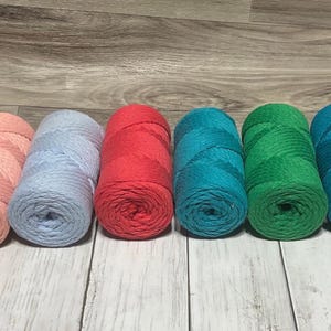 May include: Six spools of cotton rope yarn in various colors. The colors are pink, light blue, red, teal, green, and dark blue.