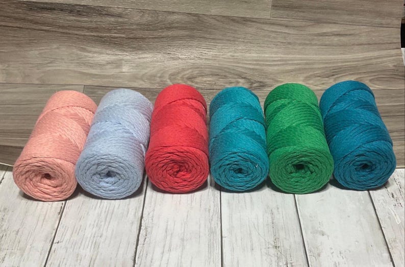 May include: Six spools of cotton rope yarn in various colors. The colors are pink, light blue, red, teal, green, and dark blue.