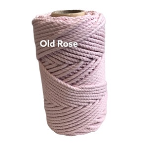 May include: A cylindrical spool of thick, twisted cord in a soft, pale pink color labeled Old Rose. The cord is wound tightly in a continuous spiral pattern around a central cardboard core, creating a textured surface with visible rope strands.