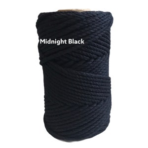 May include: A cylindrical spool of thick, braided cord in a solid midnight black color. The cord is tightly wound in a continuous pattern around a central core. The text "Midnight Black" is printed in white letters on the front of the spool.